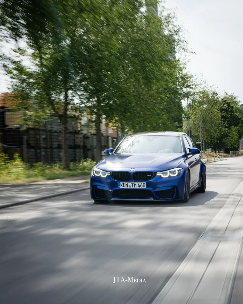 Blauer BMW auf einer Allee